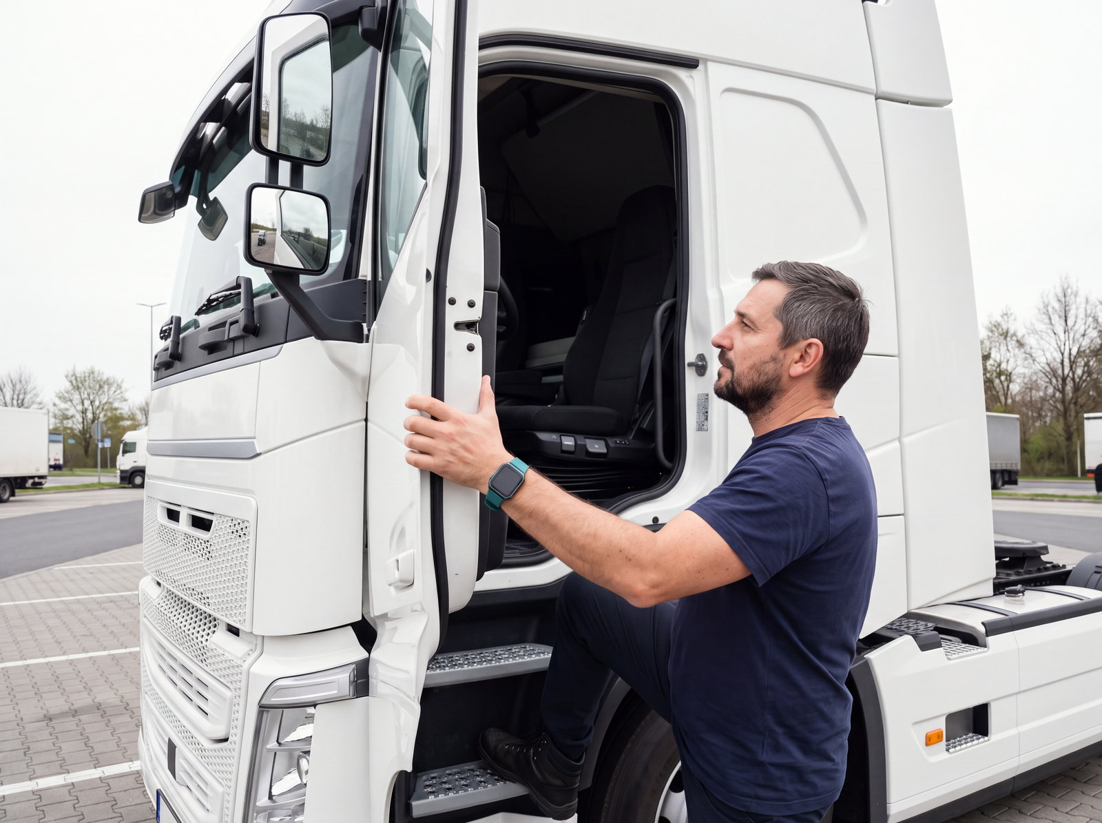 A driver climbing into the cab of a white truck at a rest area, one boot on the step, hand on the door frame