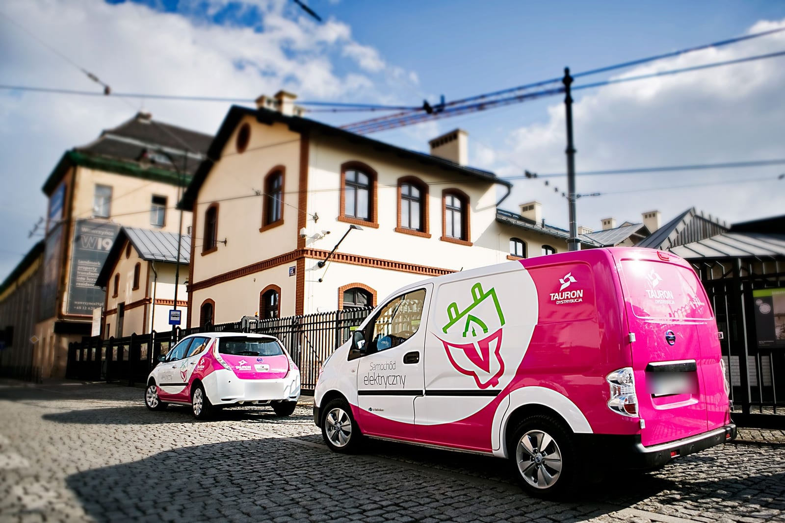 Elektryczne pojazdy dostawcze Tauron Dystrybucja zaparkowane przy ulicy